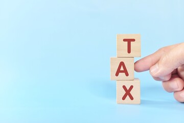 Tax reform and tax cut concept. Hand destroying a word taxes in wooden blocks.  