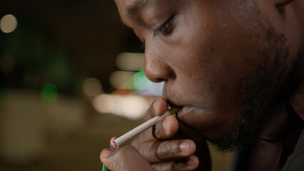Close-up portrait of an African American smoking medicinal marijuana inhales nicotine doom and...