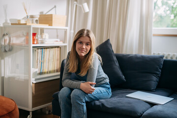 Obraz premium teenager caucasian girl sitting on sofa and looking at camera