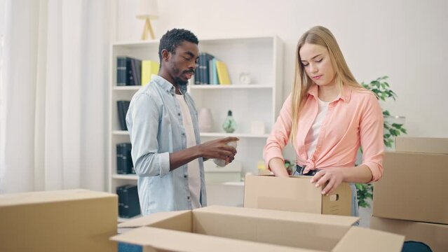 African American man and his girlfriend packing stuff in box, renting new home