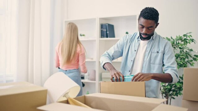 Multiethnic couple moving out of apartment together, packing belongings in box