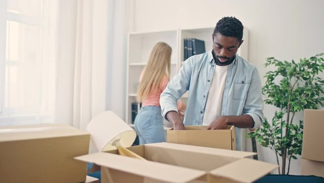 Sad interracial couple moving out of flat, packing stuff, renting new home
