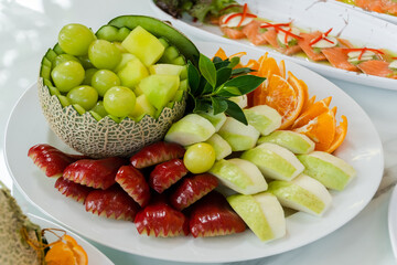 Fruit mix. rose apple, grapes, guava, melon, orange . Pieces of fruit on a plate lie on a white  background