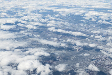 Aerial shot of snowy forested mountain tops, with stratospheric clouds