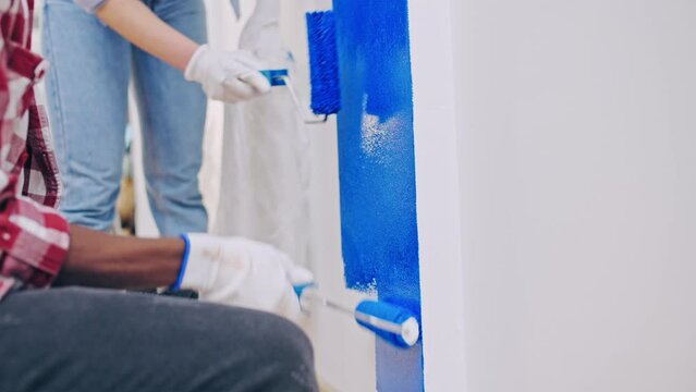 Man and woman painting walls blue using paint rollers, home repair services