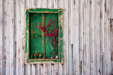 Green wooden antique window frame with shutters and decorated with flowers on steel wall plate.