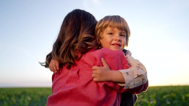 Loving smiling son hugs mom tightly. Tender family scene. Cute 3 year old kid with mother. Parenthood, childhood, happiness, children wellbeing concept.