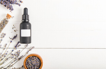 black matte bottle with a pipette with a cosmetic made of lavender on a white wooden background. top view. a copy of the space. unbranded. mosk-up.