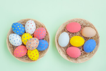 Colorful eggs in a basket on green background
