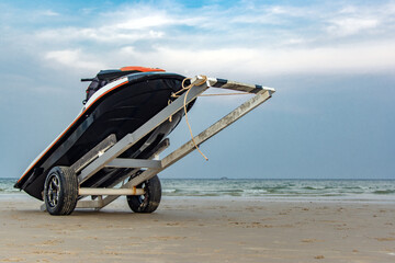 A jet ski loaded on a transit cart on a sea beach at sunset