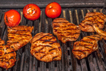 Close up view of cooking meat steak and tomatoes on grill outdoors. Sweden.