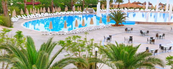 Umbrellas and sunbeds by the pool. Wide photo.