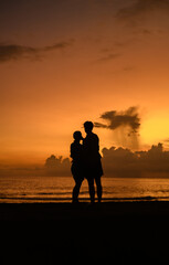 Enjoying the evening, silhouetted couple standing close to each other, Beautiful golden sunset in the background.