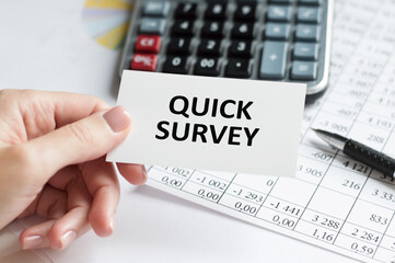 Card with text QUICK SURVEY in the hands of a person on the background of an office desk