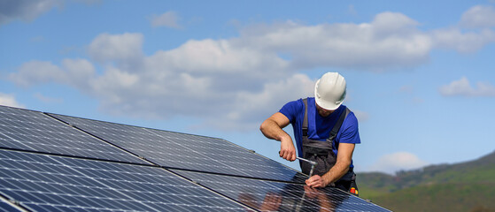 Fototapeta Man worker installing solar photovoltaic panels on roof, alternative energy concept. obraz