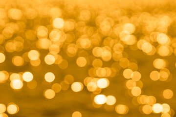 Bokeh light from reflection of golden water surface in the evening sunset