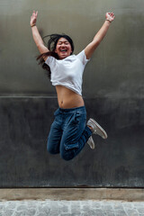 Fototapeta na wymiar Young beautiful asian woman jumping smiling in the street