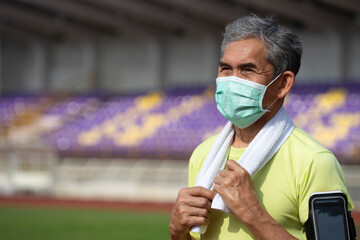 portrait senior man in sportswear wears protective face mask standing in the stadium, concept elderly people lifestyle,exercise and prevent Covid-19 pandemic