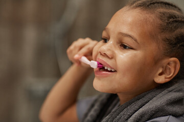Close up of little black girl brushing teeth with pink toothbrush good dental hygiene practice in childhood