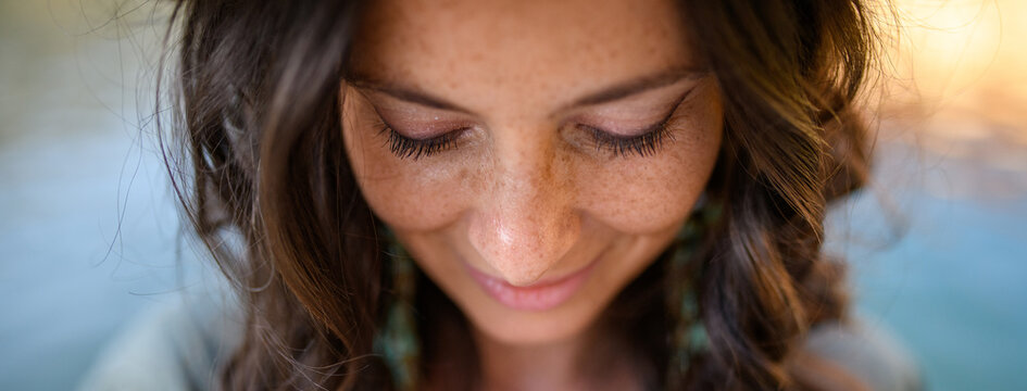 Freckles Woman Portrait. Close-up. Beautiful Dark Haired Girl With Freckles Is Looking Down On Street Background