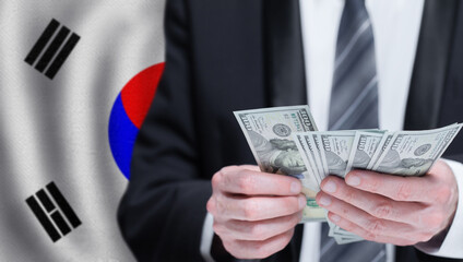 Hands holding dollar money on flag of South Korea