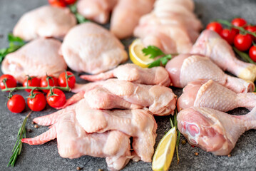Set of raw chicken fillet, thigh, wings, strips and legs on a stone background of a culinary table with spices