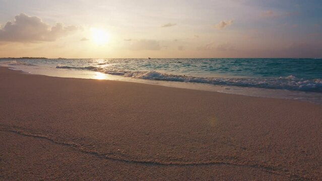 Tropical sea at sunset. Maldivian beach with gentle rolling waves on the tropical island of Thulusdhoo in Maldives