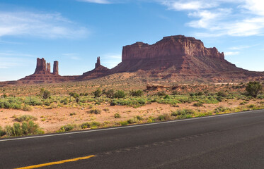 Fototapeta na wymiar Low angle shot of asphalt road near Rock Door Mesa in Monument Valley, Arizona, USA. Navajo nation area in American southwest. Famoust rock formations in Arizona desert. Red sandstone mesa.