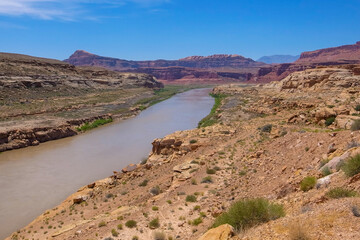 Colorado river winds through Utah desert on a very hot sunny day. Red rocks and sand in a dry country. River canyon in the desert. Geology of American west. Driving across the USA.