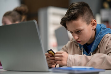 Schoolboy using computer in classroom at school