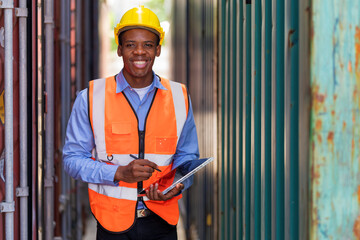 African worker using tablet working at container yard warehouse.