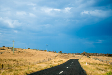 Straight open empty road surrounded by farms and fields just before the storm in Australia. Road trip travel