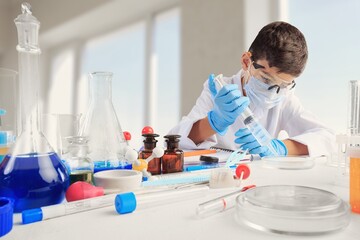Smart boy during scientific chemistry experiment wearing protection glasses, holding bottle with liquid. chemical equipment on school lesson portrait