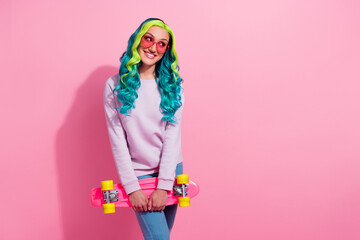 Portrait of positive pretty girl hold skateboard toothy smile look empty space isolated on pink color background