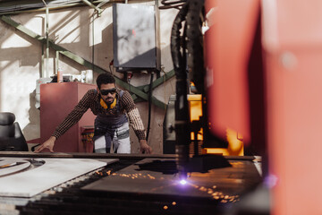 Man working on laser cutter of metal, modern technology in process at metalworking manufacturing...