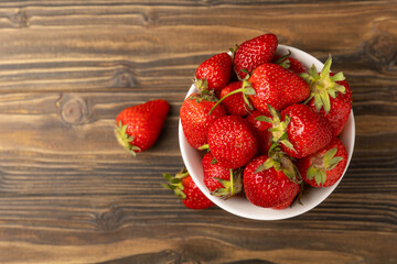 Fresh ripe juicy strawberries in a bowl on a brown wooden table. Summer background composition with strawberries. Fruit concept.Vitamins.Eco berries. Copy space