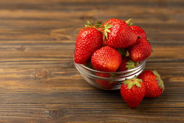 Fresh ripe juicy strawberries in a bowl on a brown wooden table. Summer background composition with strawberries. Fruit concept.Vitamins.Eco berries. Copy space