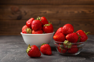 Fresh ripe juicy strawberries in a bowl on a black cement table. Summer background composition with strawberries. Fruit concept.Vitamins.Eco berries. Copy space