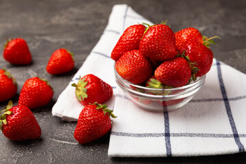 Fresh ripe juicy strawberries in a bowl on a black cement table. Summer background composition with strawberries. Fruit concept.Vitamins.Eco berries. Copy space