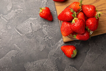 Fresh ripe juicy strawberries in a bowl on a black cement table. Summer background composition with strawberries. Fruit concept.Vitamins.Eco berries. Copy space