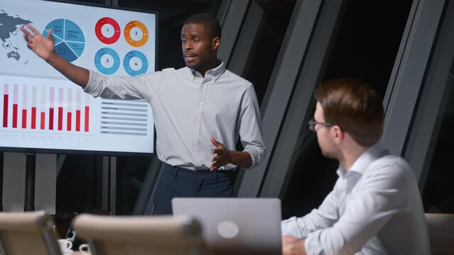 Young african american man giving presentation to corporate leader using tv multimedia in meeting room
