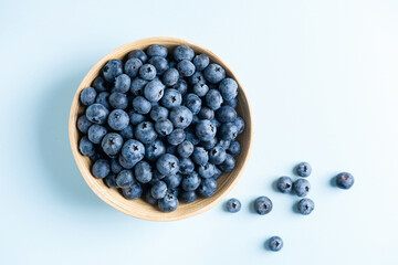Organic blueberries in bowl on blue gradient background, top view copy space