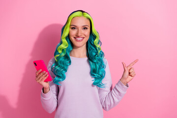 Portrait of attractive cheerful person hold telephone indicate finger empty space isolated on pink color background