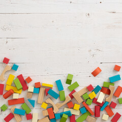 Top view of multi-colored wooden blocks scattered on a white wooden table. School, education and training concept. Home games during self-isolation and pandemic
