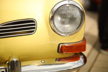 Vintage Yellow Classic Car Front Close-Up with Headlight and Chrome Details