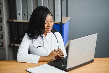 healthcare, medical and technology concept - african female doctor with laptop