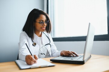 healthcare, medical and technology concept - african female doctor with laptop