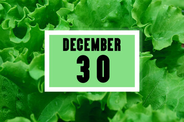 calendar date oncalendar date on the background of green lettuce leaves. December 30 is the thirtieth day of the month