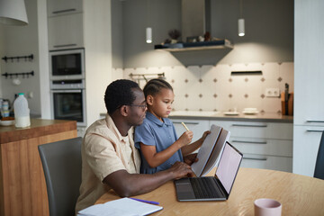 Side view portrait of caring black father helping little girl with homework in cozy scene, copy...