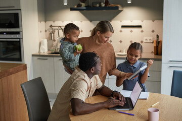 Portrait of multiethnic family with two kids in home interior black and Caucasian parent couple